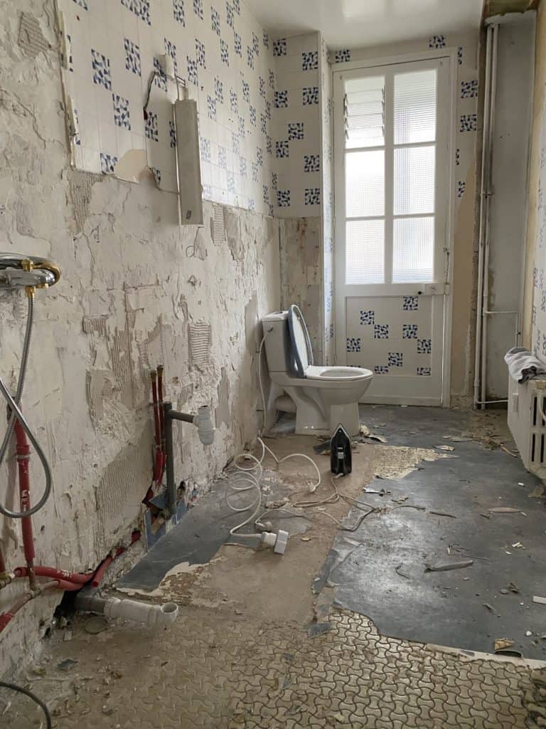 Salle de bain en phase de démolition murs papier peint