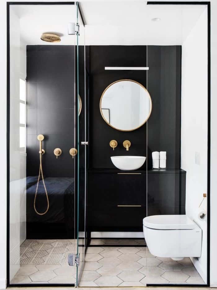 Salle de bain minimaliste robinetterie dorée mur noir toilettes suspendues