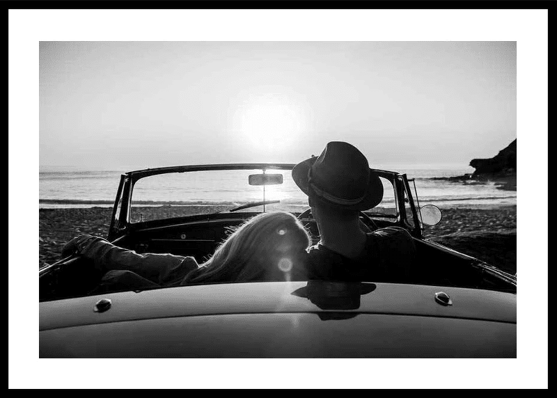 Affiche en noir et blanc d'un couple regardant un coucher de soleil dans une voiture sur une plage