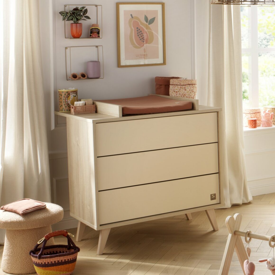 Commode bébé en bois clair avec plan à langer intégré, dans une chambre bébé à la décoration naturelle et aux tons doux.
